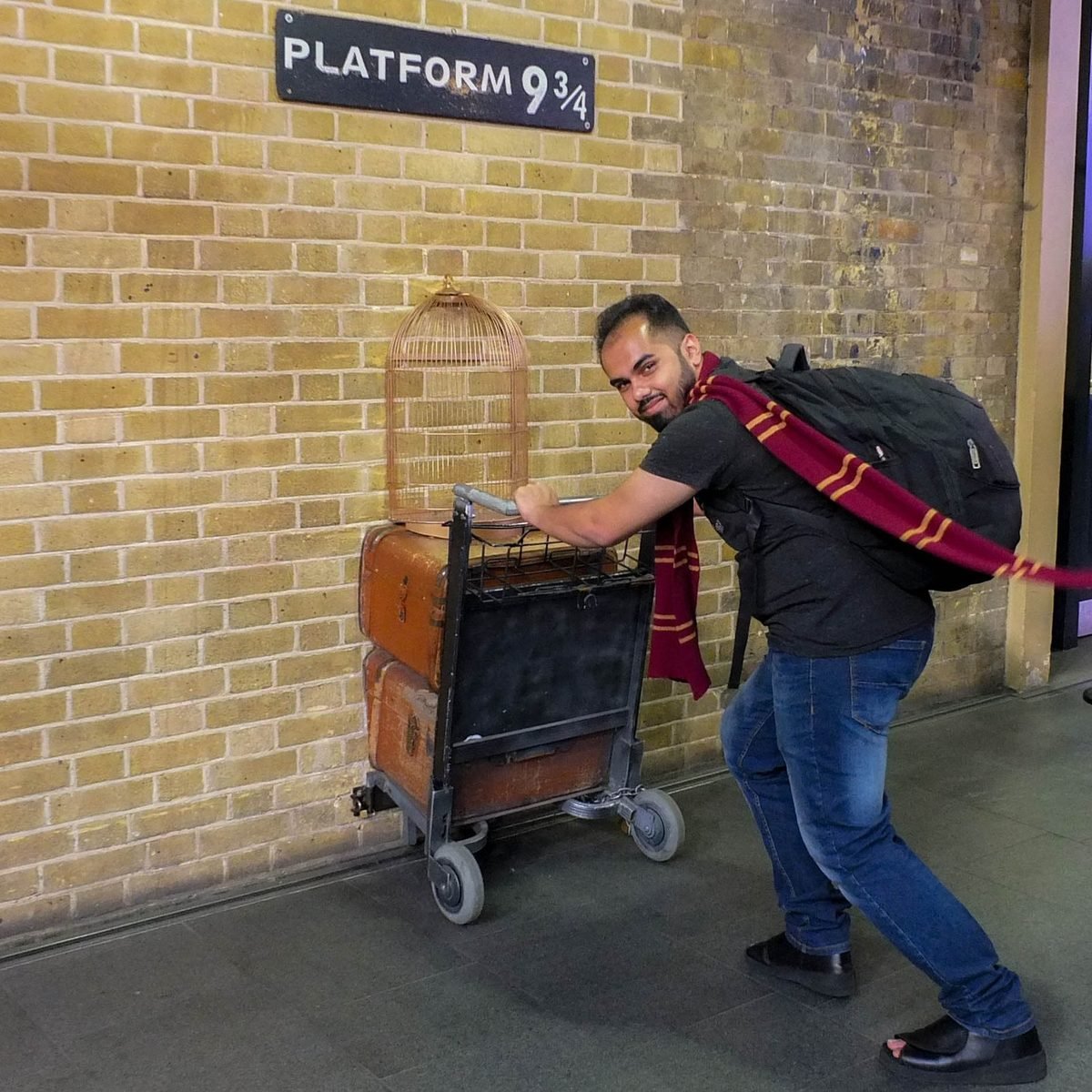 Mihir Kelkar (GPSBABA) at Platform 9¾, King's Cross, London, pushing a luggage trolley into the brick wall