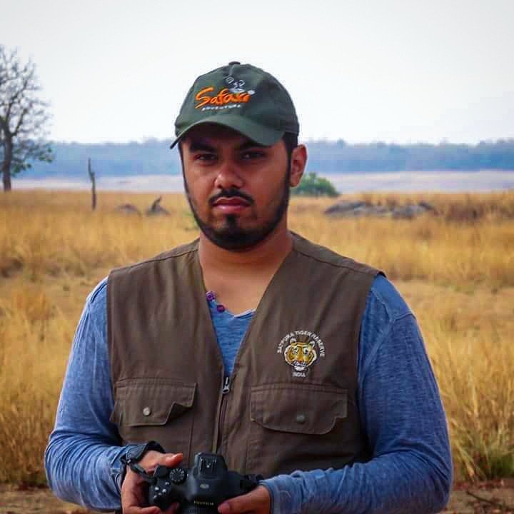 Mihir Kelkar (GPSBABA) on safari in a green cap and Satpura Tiger Reserve vest, holding a camera
